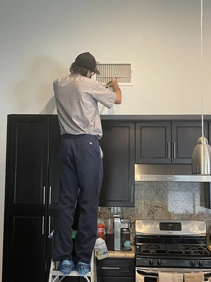 Technician inspecting an air vent during HVAC service in Woodlawn